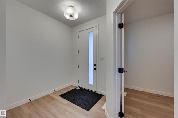 Entryway with a white door, a black mat, and a modern ceiling light. - 10 Owl Ridge Cl, Fort Saskatchewan