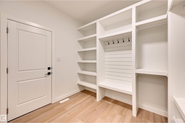 Mudroom with a white door, a built-in bench, and extensive white shelving and storage. - 10 Owl Ridge Cl, Fort Saskatchewan