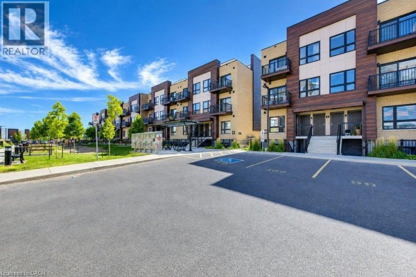 Exterior view of townhouse units with paved parking lot and blue sky. - 10 Palace Street Unit# D16, Kitchener