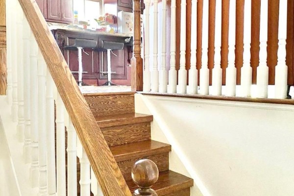 Wooden staircase with white spindles leading up towards a kitchen area with island. - 10 Parkdene Court, Toronto