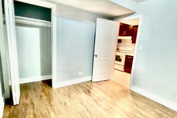 Room with light blue walls, wood laminate flooring, and a doorway to the kitchen. - 10 Parkdene Court, Toronto