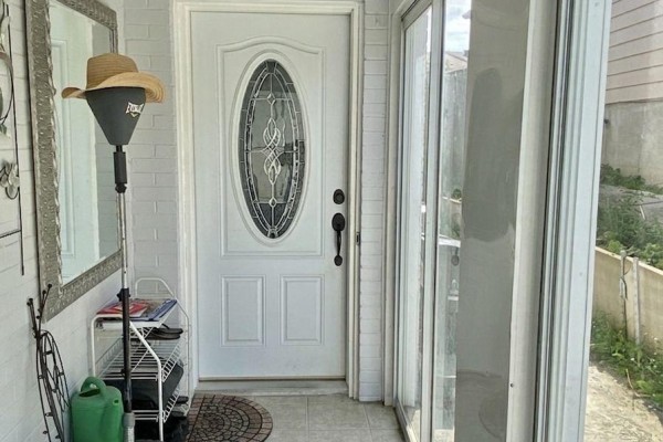 Front entrance with a white oval glass door, adjacent window, and decorative mirror. - 10 Parkdene Court, Toronto