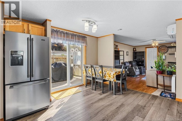 Living room with two brown recliners, a sofa, patterned rug, and wooden floor. - 10 Peridot Street, Moncton