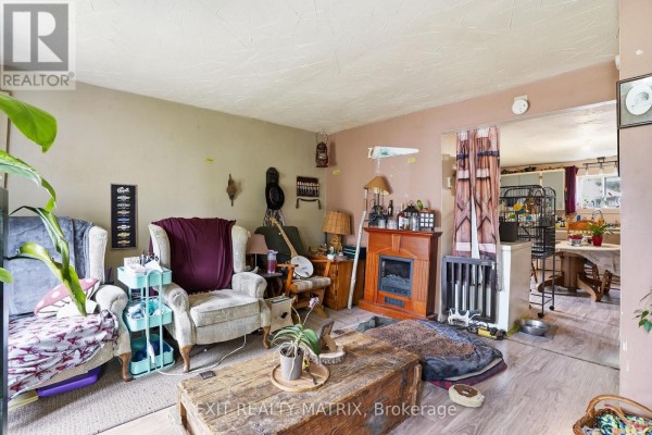 Living room with two armchairs, a coffee table, a fireplace, and a view into the dining area. - 10 Peter Street, Champlain