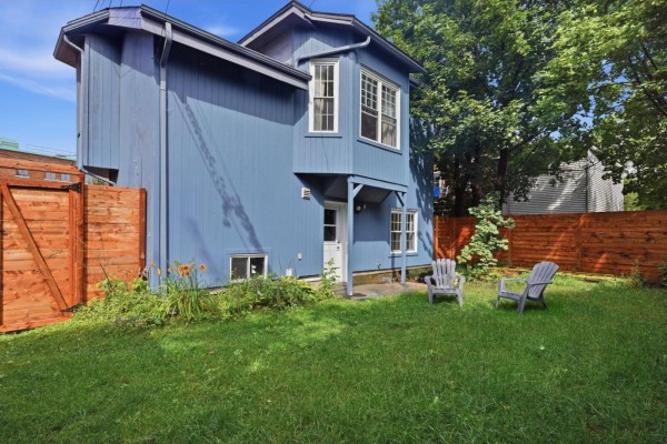 Blue exterior of a house with a grassy backyard and two grey Adirondack chairs. - 10 Rue De Carillon, Gatineau