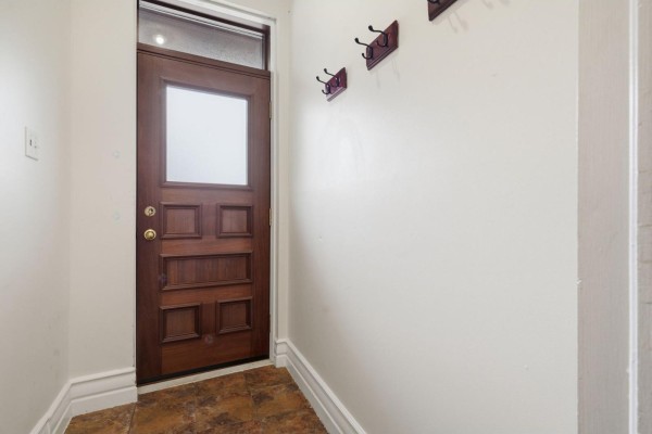 Interior view of a dark wood paneled front door with frosted glass and coat hooks. - 10 Rue De Carillon, Gatineau