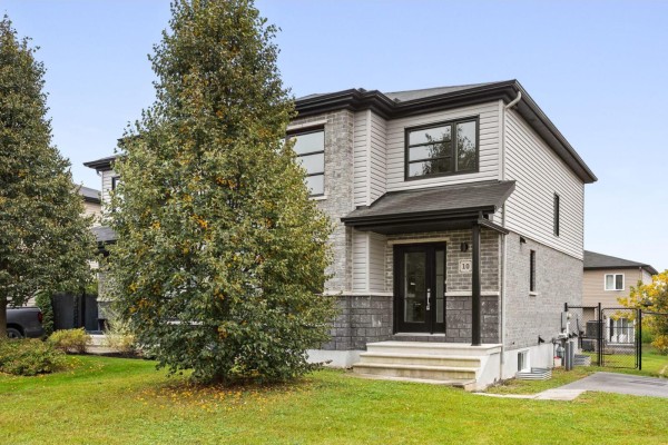Front exterior view of a modern two-story house with grey stone and siding during the day. - 10 Rue De L'empire, Gatineau