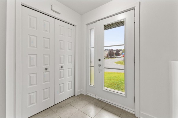 Interior view of an entryway with a double white closet and glass front door. - 10 Rue De L'empire, Gatineau