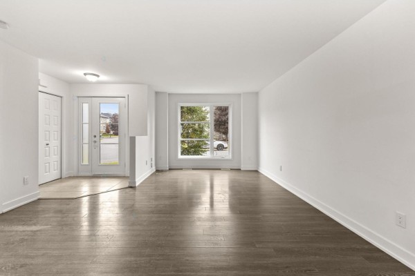 Interior view of a spacious living room with dark wood floors and large windows. - 10 Rue De L'empire, Gatineau
