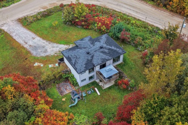 Aerial view of a white house with a dark roof, showing a backyard deck, play structure, and surrounding fall foliage. - 10 Rue Lesage, Cantley
