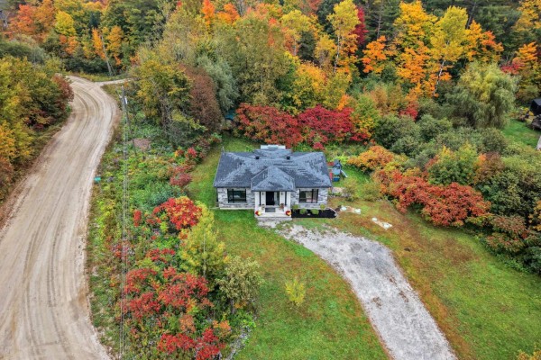 Overhead view of a house nestled among vibrant red and orange autumn trees, with a gravel driveway. - 10 Rue Lesage, Cantley