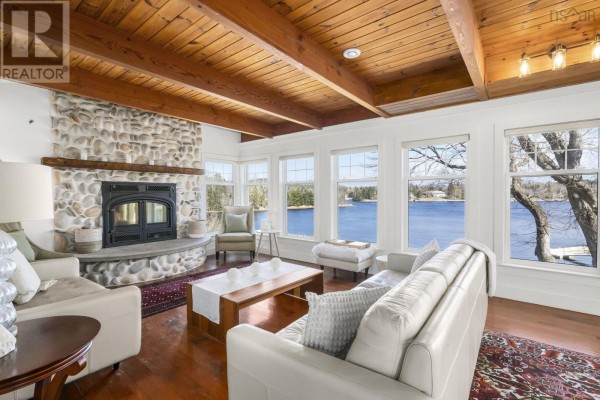 Living room with white sofas, wood beamed ceiling, and panoramic windows overlooking the water. - 10 Schooner Cove Road, Head Of St  Margarets Bay