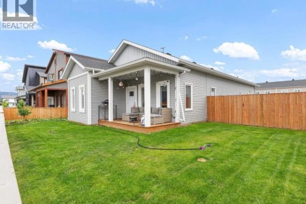 Backyard view of a light gray house with a covered wooden deck and outdoor furniture. - 10 Scotia Lane, Whitehorse