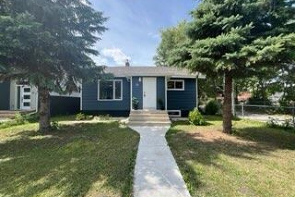 Detached garage with dark blue siding and a black sectional garage door. - 10 St Louis Road, Winnipeg