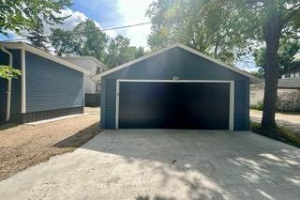 Rear view of the house, showing dark blue siding and a stuccoed garage. - 10 St Louis Road, Winnipeg
