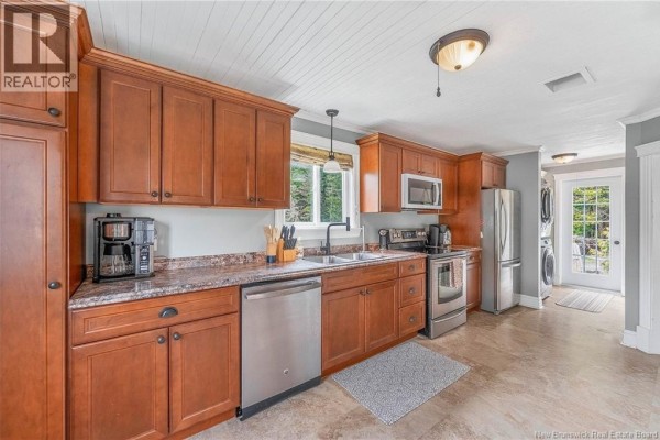 Kitchen with dark wood cabinets, stainless steel appliances, granite countertops, and a view out the window. - 10 Stanley Oliver Road, Back Bay