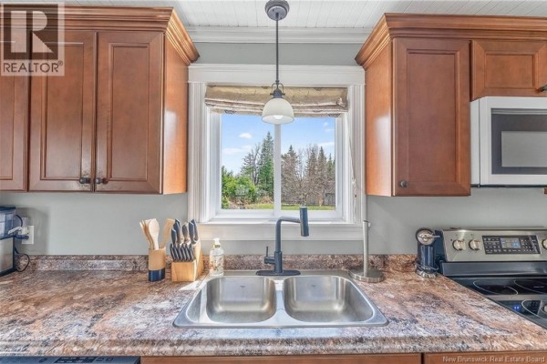 Close-up of a double sink in the kitchen, with a window view of trees and a dark wood cabinet. - 10 Stanley Oliver Road, Back Bay