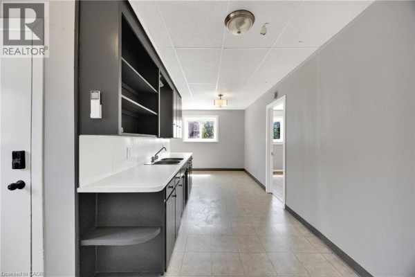 Side view of a kitchen area with dark cabinets, white countertop, and tiled floor. - 10 Venison Street W, Tillsonburg