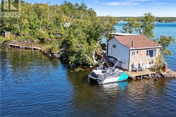 Cottage on a small island with a boat and dock on the water. - 10 Whitson Lake Landing, Val Caron
