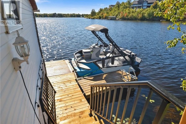 Wooden dock with a boat and stairs leading to a cottage. - 10 Whitson Lake Landing, Val Caron