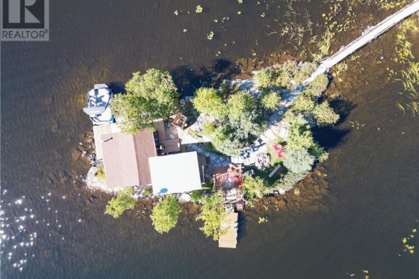 Aerial view of a small island with a bridge, cottage, and boat. - 10 Whitson Lake Landing, Val Caron