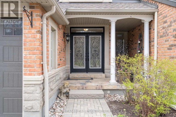 Entrance detail of a townhouse featuring double glass doors, stone accents, and decorative columns. - 10 Wilton Trail, Aurora