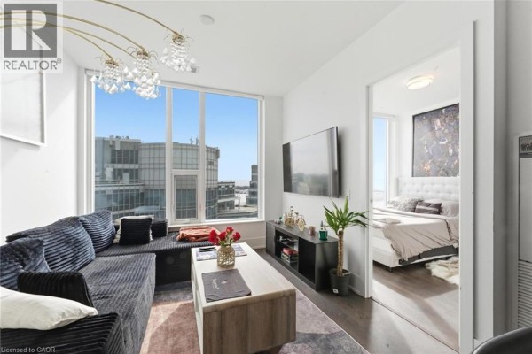 Living room with sectional sofa, wall-mounted TV, and view of adjacent bedroom - 10 York Street Unit# 3807, Toronto