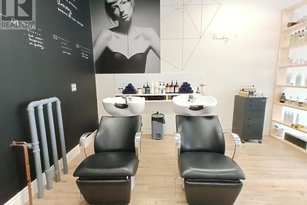 Hair washing stations with black leather chairs and sinks in a salon. Black accent wall with art and shelving. - 100 - 100 Murray Street, Ottawa