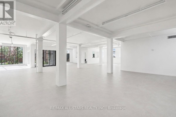 Wide-angle view of an empty commercial space with light wood-look flooring and white walls. - 100 - 14 Mccaul Street, Toronto