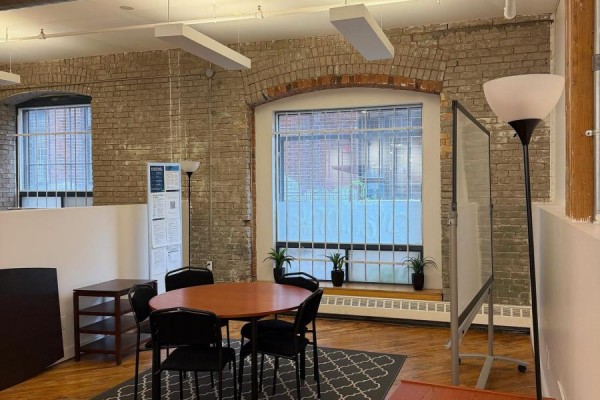 Small meeting room with a round table, chairs, and brick accent wall. - 100 - 20 Maud Street, Toronto