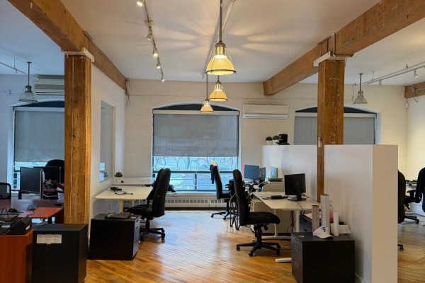 Office interior with workstations, exposed beams, and large windows with blinds. - 100 - 20 Maud Street, Toronto