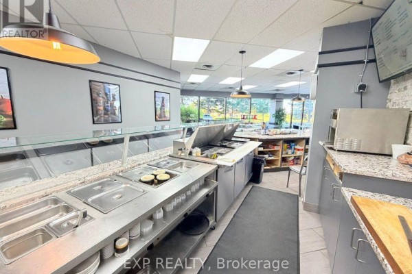 Food service counter with stainless steel sinks and warming trays in a commercial kitchen. - #100 - 700 Dorval Drive, Oakville
