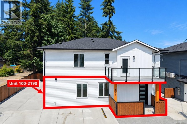 Exterior of a white duplex with white horizontal siding, large windows, and a black railing balcony. - 100 2190 Jingle Pot Rd, Nanaimo
