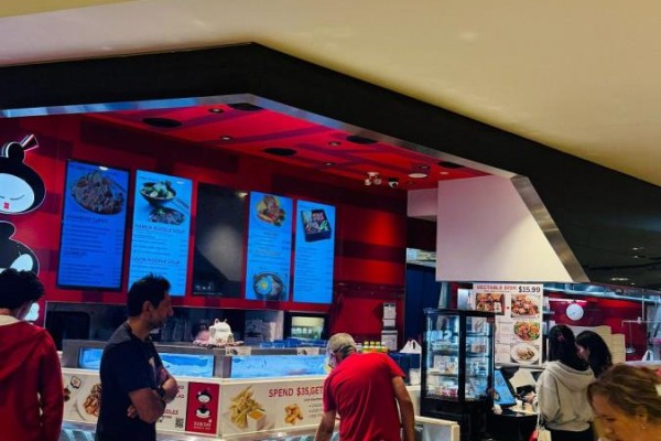 Interior view of a sushi and noodle bar with digital menu boards displaying food items. - 100 City Centre Drive, Mississauga
