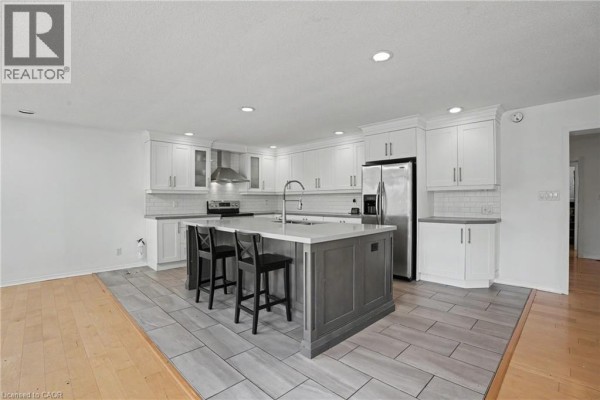 Open concept kitchen and living space with a large island and hardwood flooring. - 100 Hardale Crescent, Hamilton