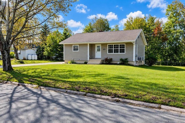 Exterior of a beige bungalow on a green lawn with trees and a blue sky. - 100 High Street, Stellarton
