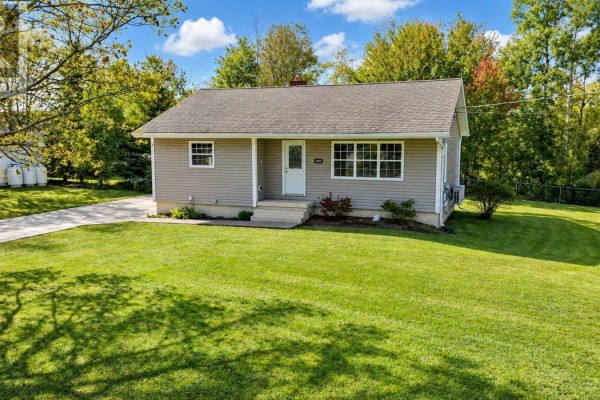 View of the beige bungalow's front entrance and tidy green lawn. - 100 High Street, Stellarton