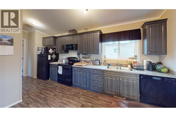Living room with sofas, a coffee table, and a large window. - 100 Industrial #1 Road Unit# 55, Sparwood