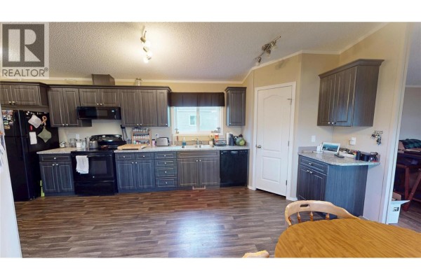 Living room with a bookshelf, a cat tree, and a TV. - 100 Industrial #1 Road Unit# 55, Sparwood