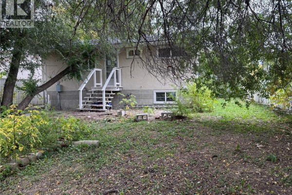 Side view of the house with a wooden staircase leading to the backyard. - 100 Marshall Crescent, Regina