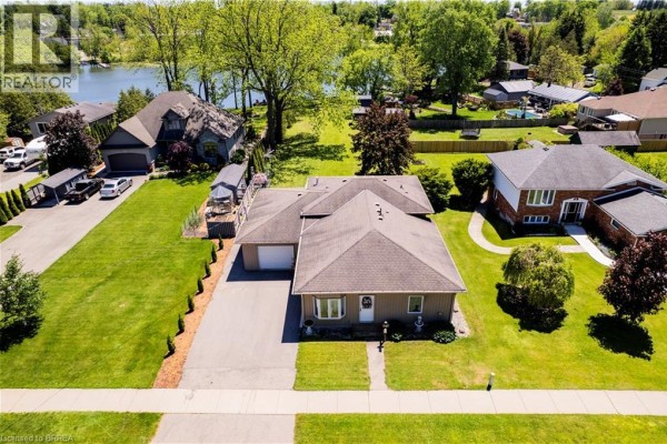 Aerial view of a beige bungalow with a garage and driveway on a grassy lot. - 100 Mechanic Street W, Waterford