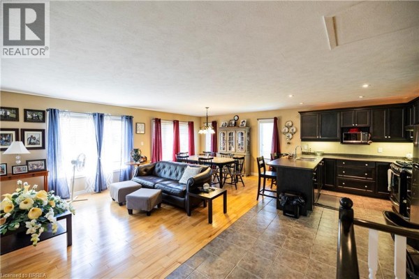 Open concept living, dining, and kitchen with leather sofa, dining set, and dark wood cabinets - 100 Mechanic Street W Waterford