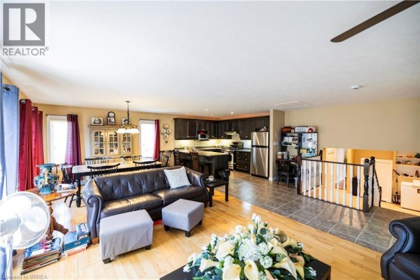 Open concept living, dining, and kitchen with leather sofa, dining table, and dark wood cabinets - 100 Mechanic Street W Waterford