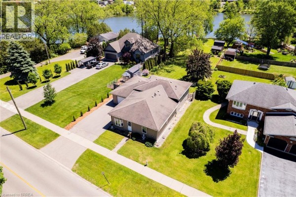 Aerial view of a beige bungalow with a garage, driveway, and grassy lot. - 100 Mechanic Street W, Waterford