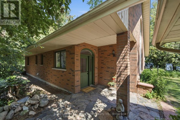 Entrance to a house with a green door, brick exterior, and a stone walkway. - 100 Pinewood Boulevard, Kawartha Lakes