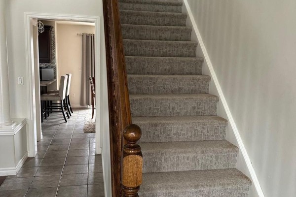 A kitchen with dark wood cabinets, stainless steel appliances, and a large island with stools. - 100 Southview Court, Woodstock