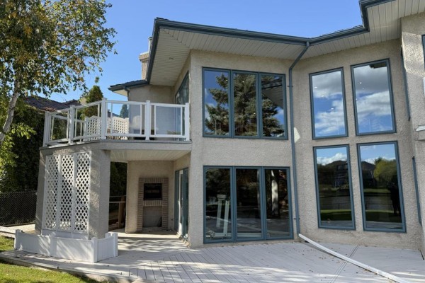 Close-up view of the rear exterior, showing a balcony with glass railing and an outdoor fireplace. - 100 Vanderbilt Drive, Winnipeg