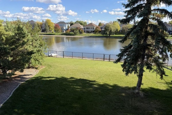 View of a lake and treed backyard from a deck of the house. - 100 Vanderbilt Drive, Winnipeg
