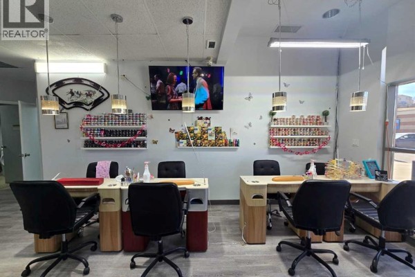 Manicure stations facing a wall with shelves of nail polish bottles and a TV. - 1000 Hamptons Drive Nw, Calgary