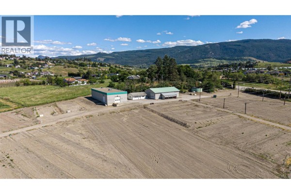 Fenced backyard with a covered swimming pool and a view of rolling hills under a cloudy sky. - 10003 6 Highway, Coldstream
